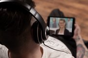 PhotoSwipe1.jpg Beispielfoto: Blick von oben rechts über die Schulter. Ein Mensch mit Headset im Austausch mit einer ebenfalls mit Headset ausgestatteten Person auf dem Bildschirm seines Tablets.