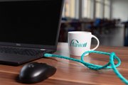 PhotoSwipe2.jpg Beispielfoto: Auf einem braunen Tisch steht ein geöffneter Laptop samt Maus sowie eine weiße Kaffeetasse mit dem Logo der faw.
