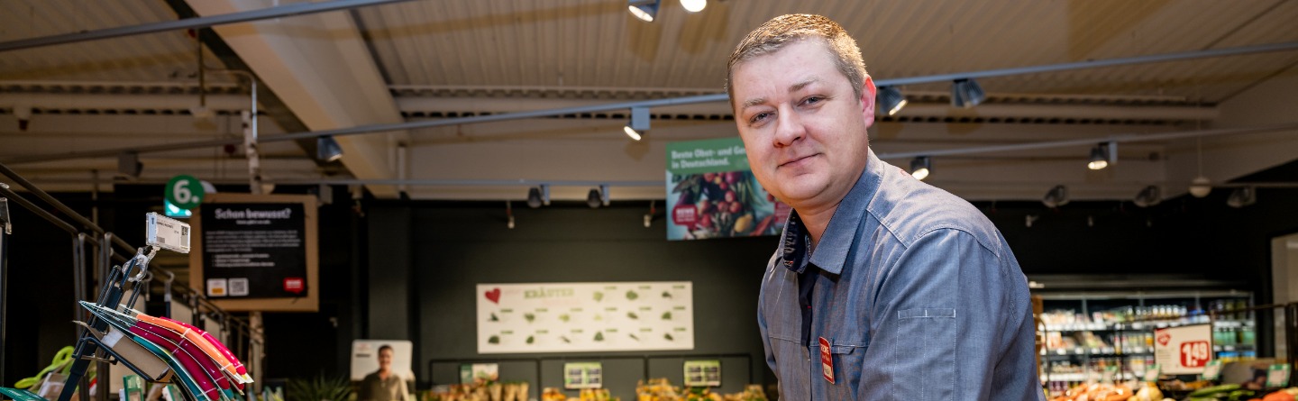 Ein Mann arbeitet in einer Filiale der Supermarkt-Kette Rewe an einer Frischetheke