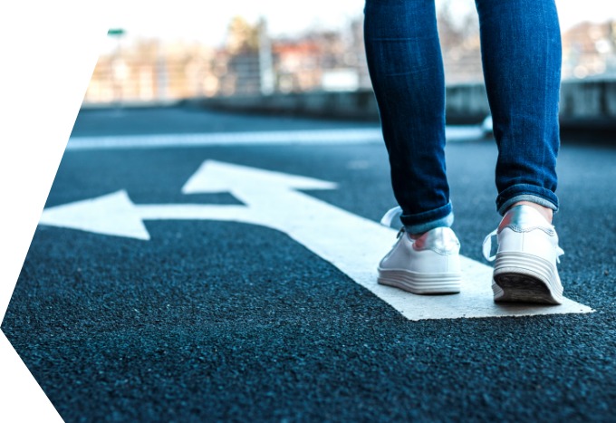 faw Dessau Ein Mensch läuft über eine Straße, auf die ein weißer Pfeil gemalt wurde. Die Pfeilspitzen zeigen nach vorn und nach links.